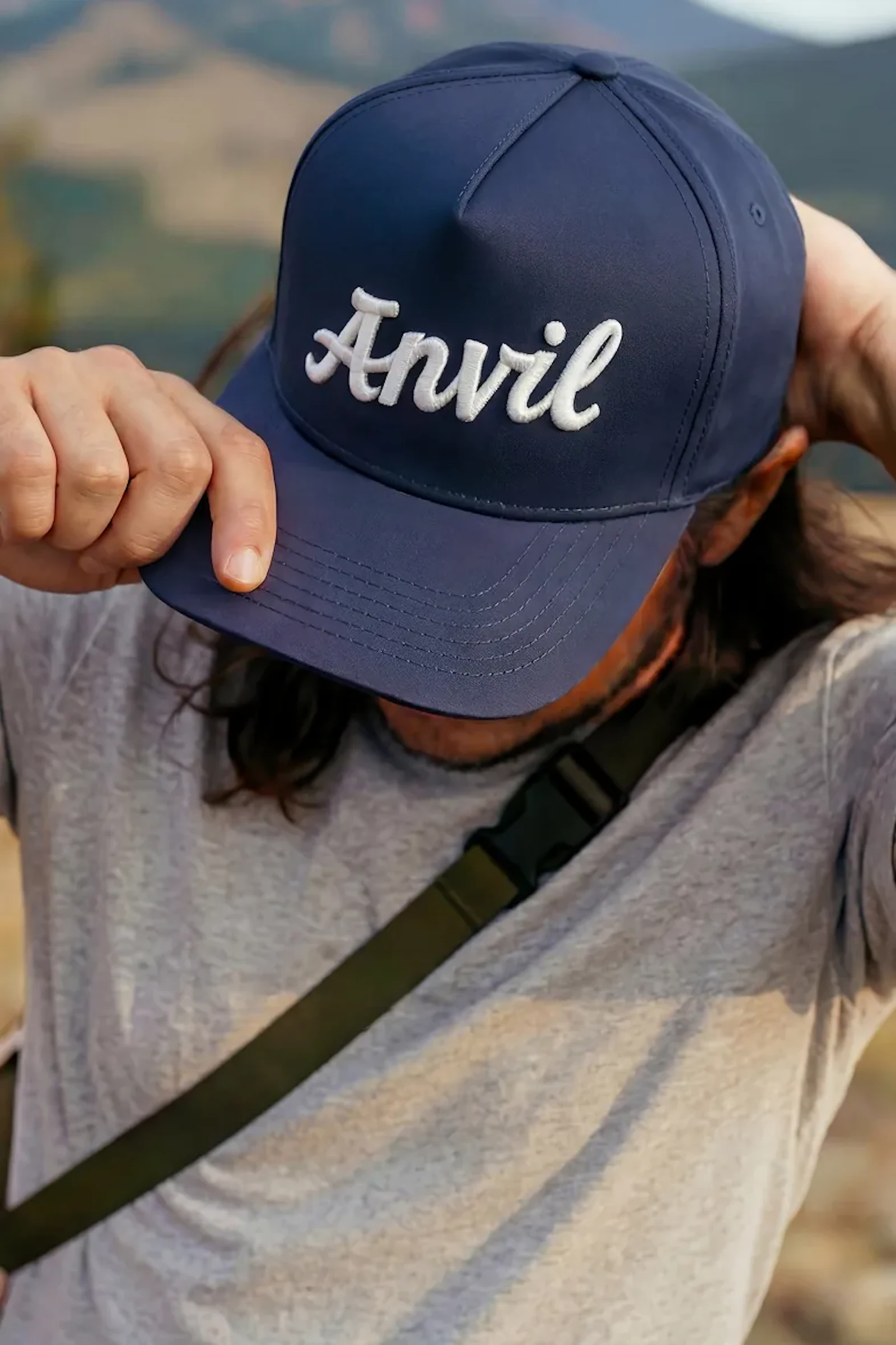 Man wearing a navy Anvil baseball cap