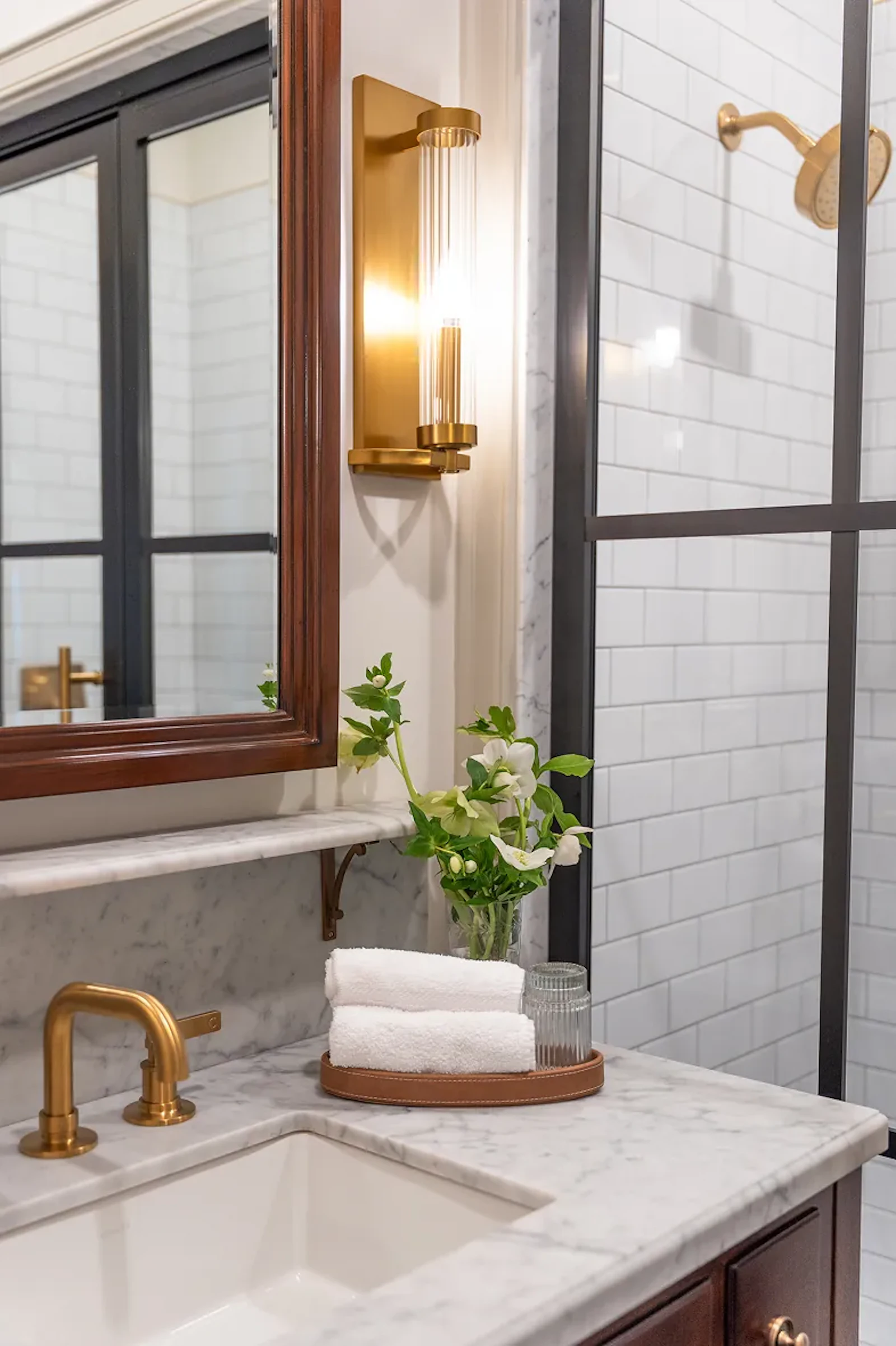 Marble bathroom vanity with brass fixtures and folded white towels