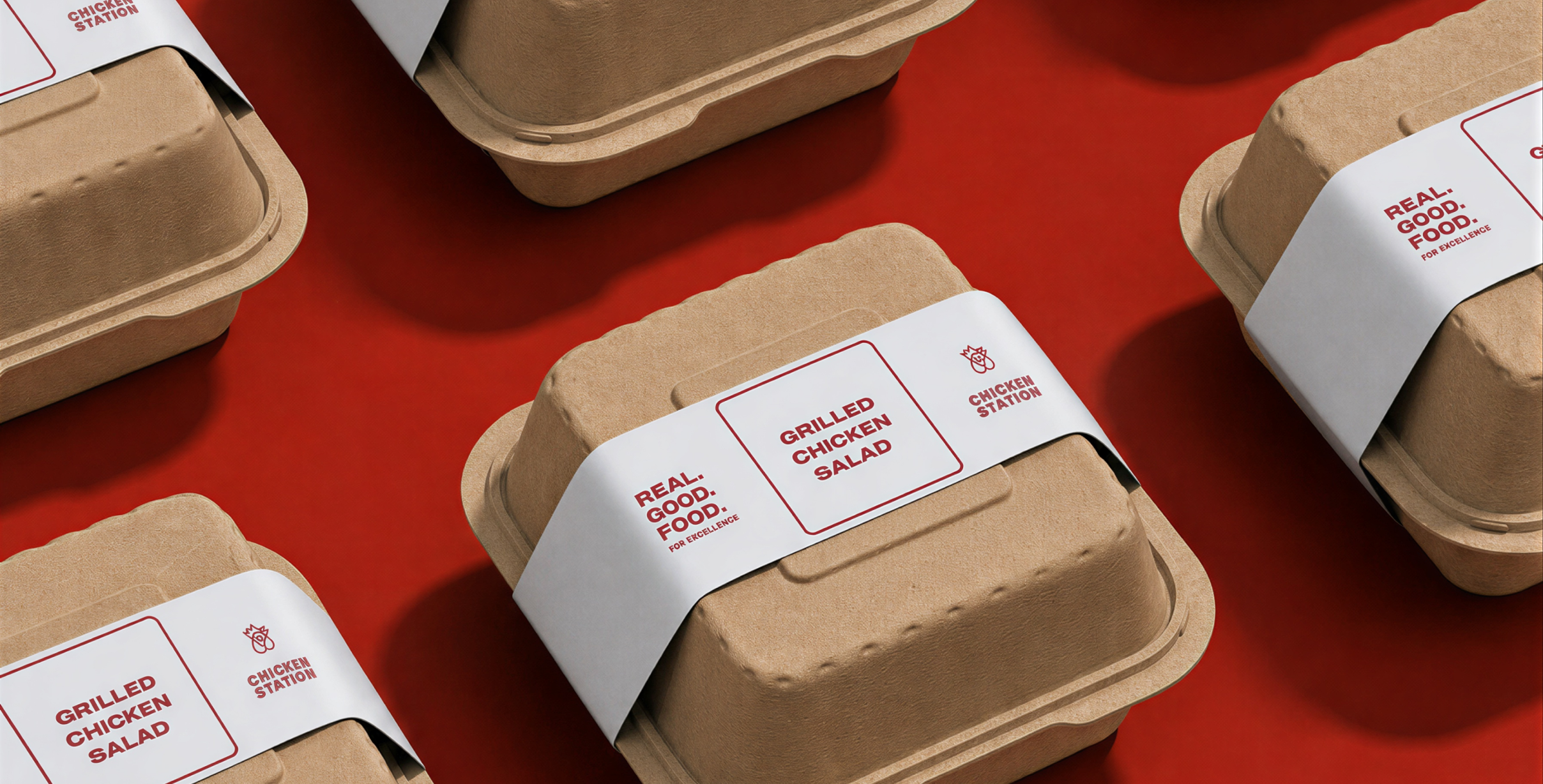 Cardboard takeout containers with white and red branding text including "Chicken Station," "Grilled Chicken Salad," and "Real Good Food for Excellence," arranged on a red surface.