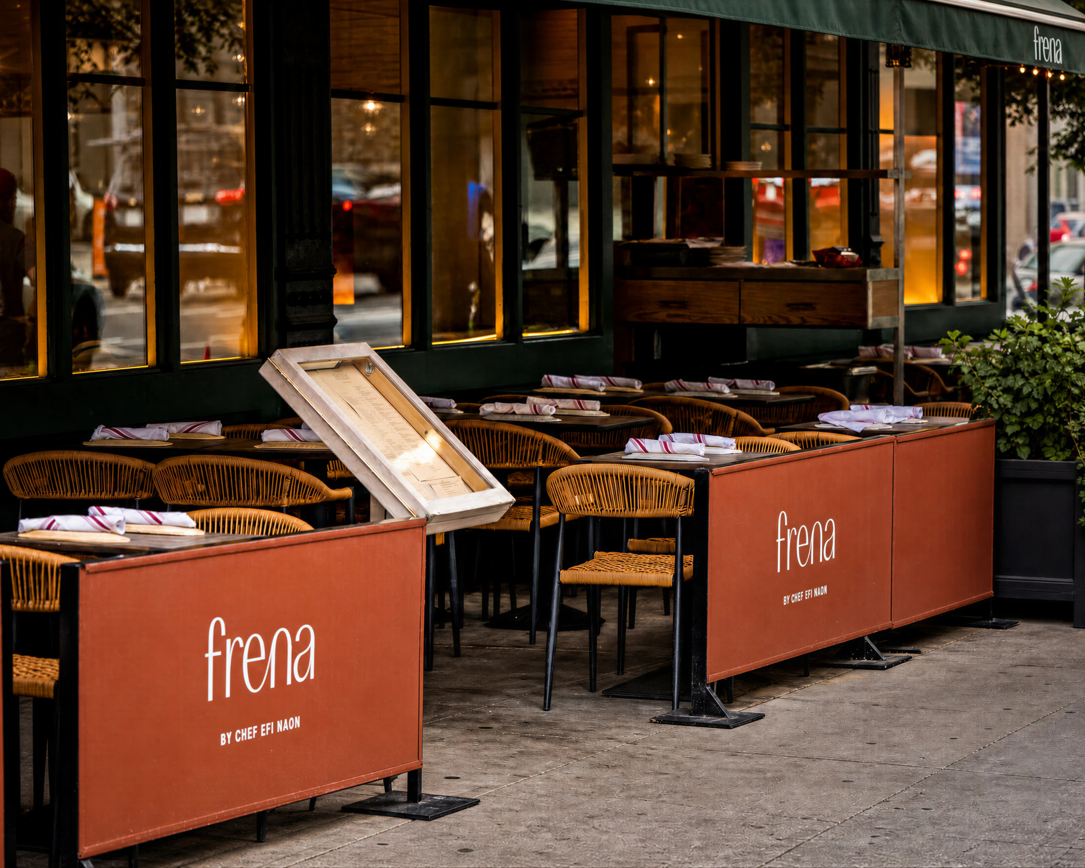 Outdoor restaurant patio with tables and chairs, featuring large orange sign panels