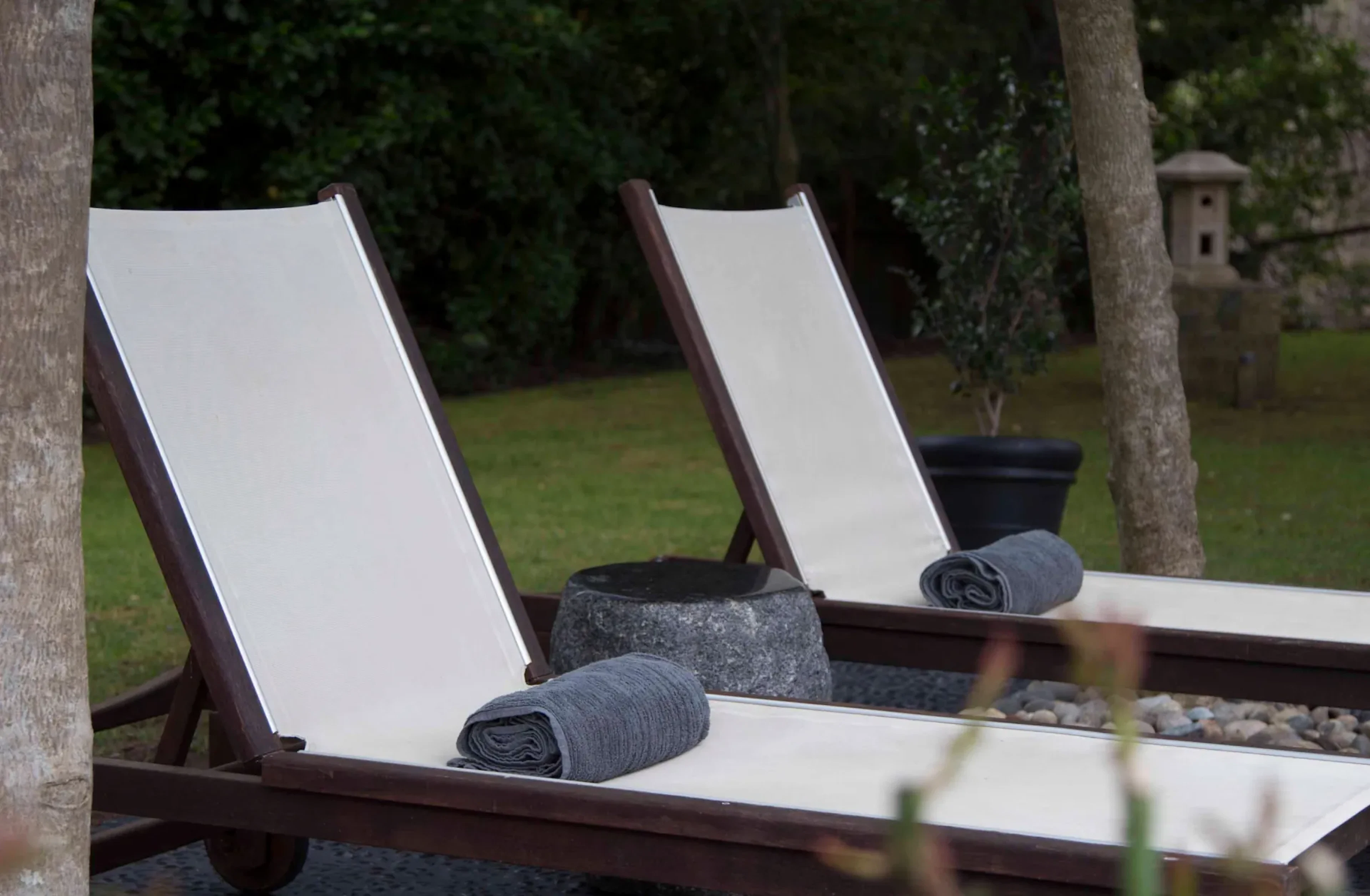 Rolled towels on wooden lounge chairs by a lawn