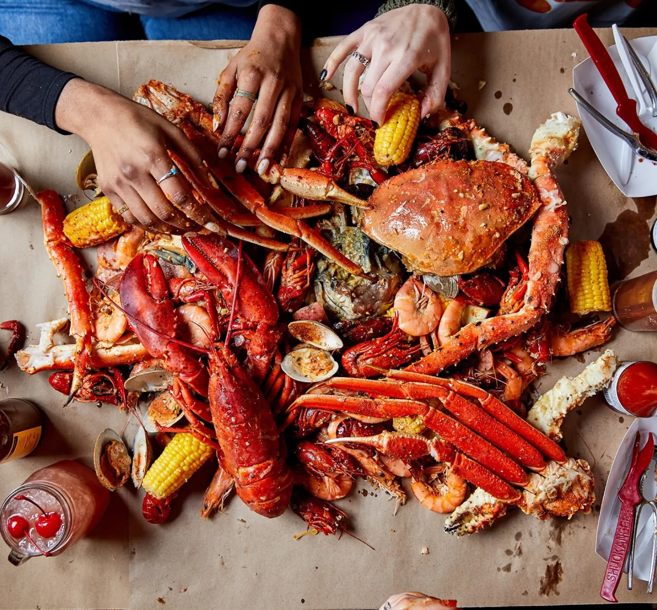 Hands reaching into a seafood boil spread
