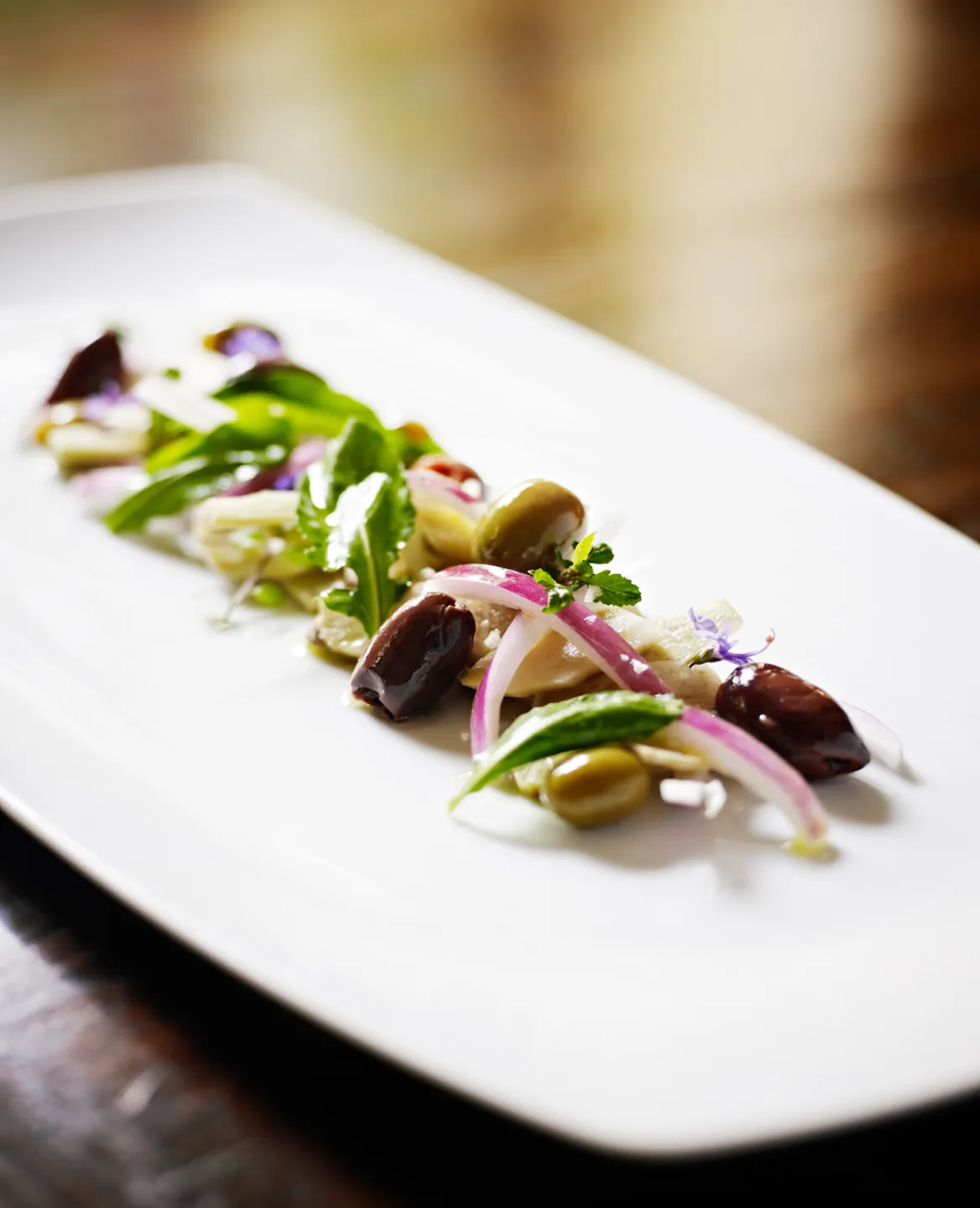 Plated salad with olives, red onion, and greens