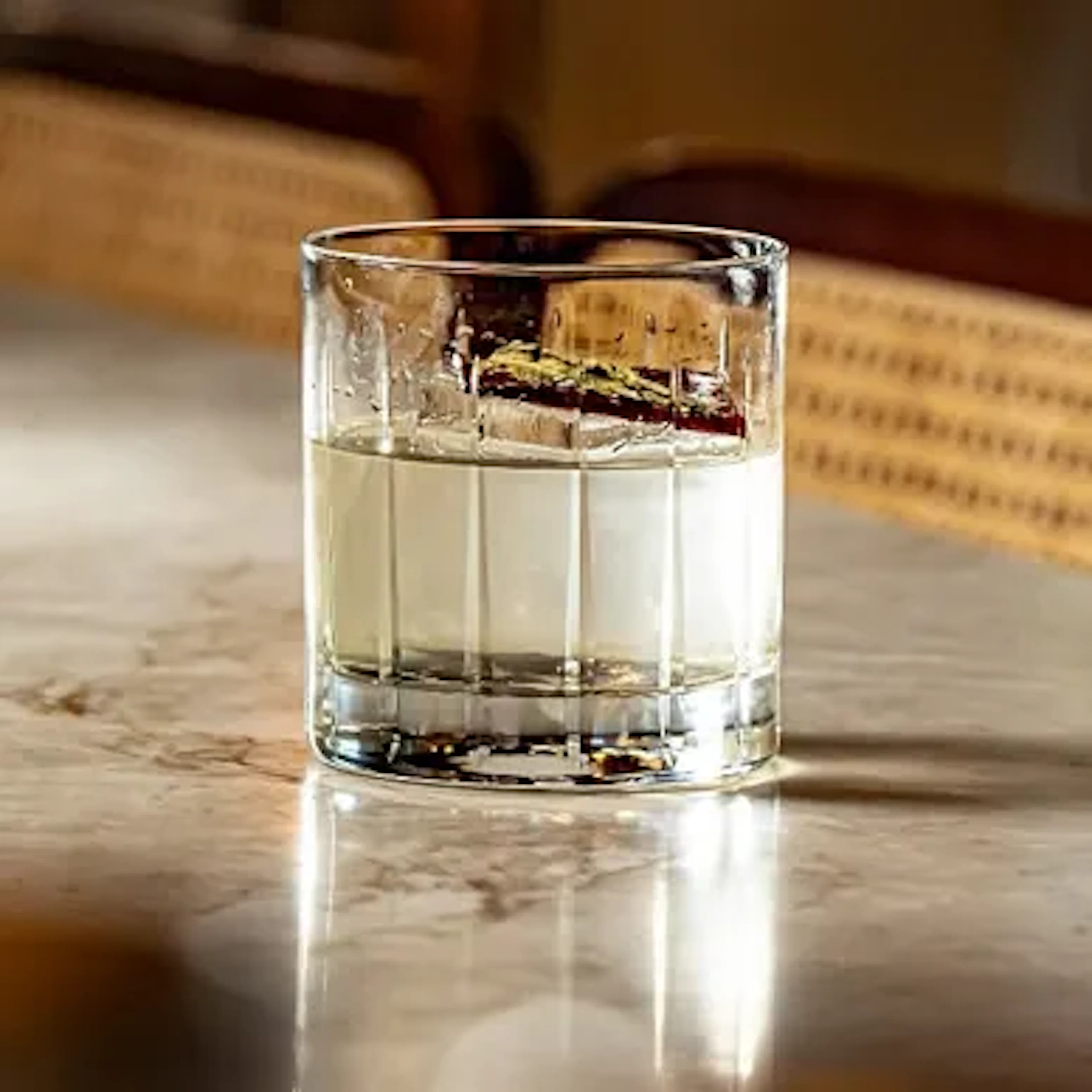 Cocktail glass with a large ice cube on a marble table