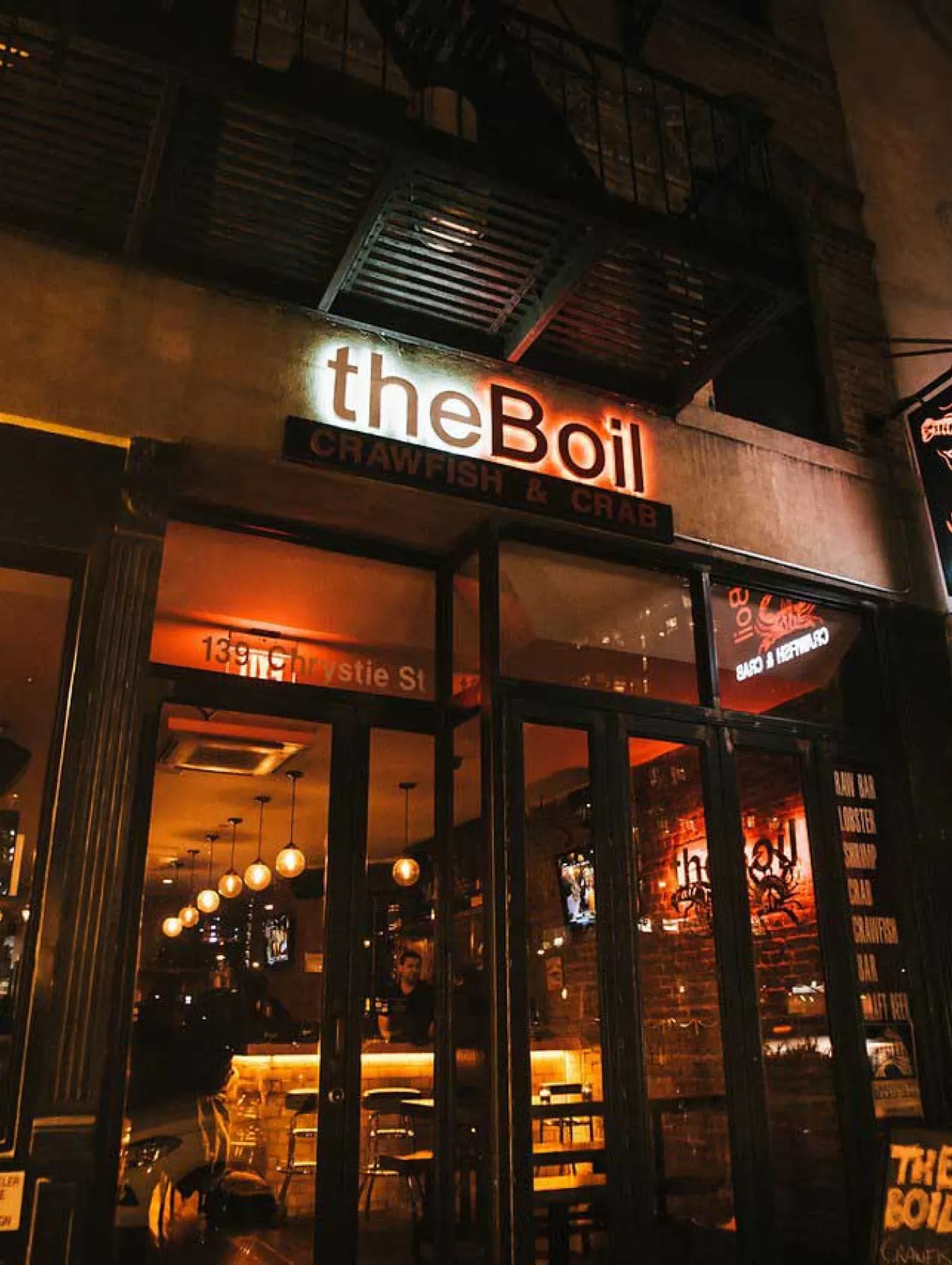 The Boil storefront sign lit up at night