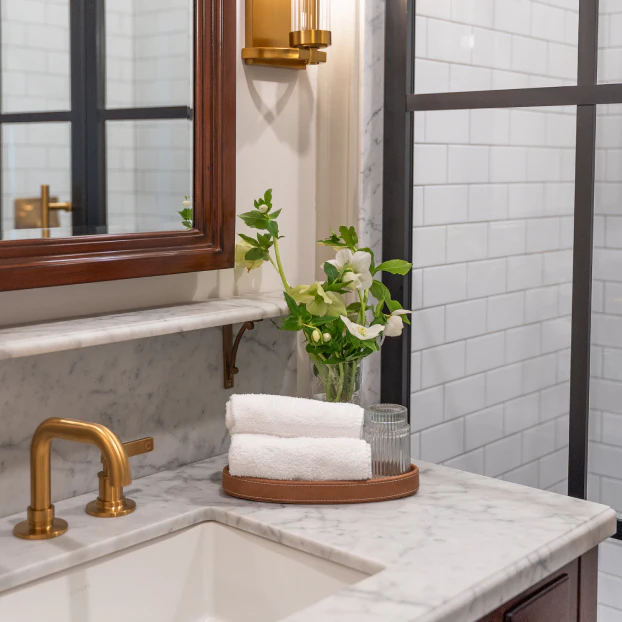 Marble bathroom vanity with brass fixtures and folded white towels