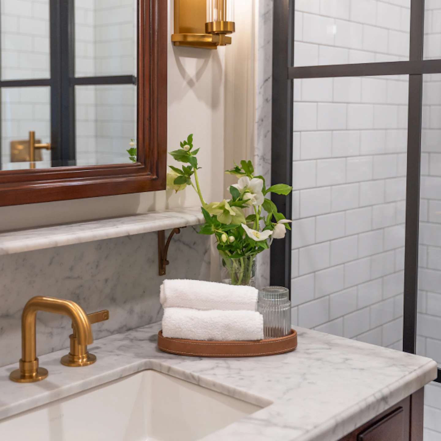 Marble bathroom vanity with brass fixtures and folded white towels