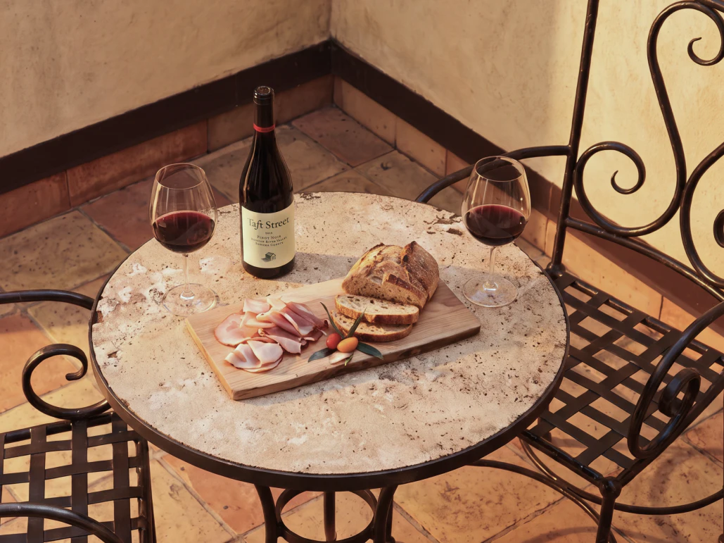 Wine bottle, glasses and bread board on outdoor table