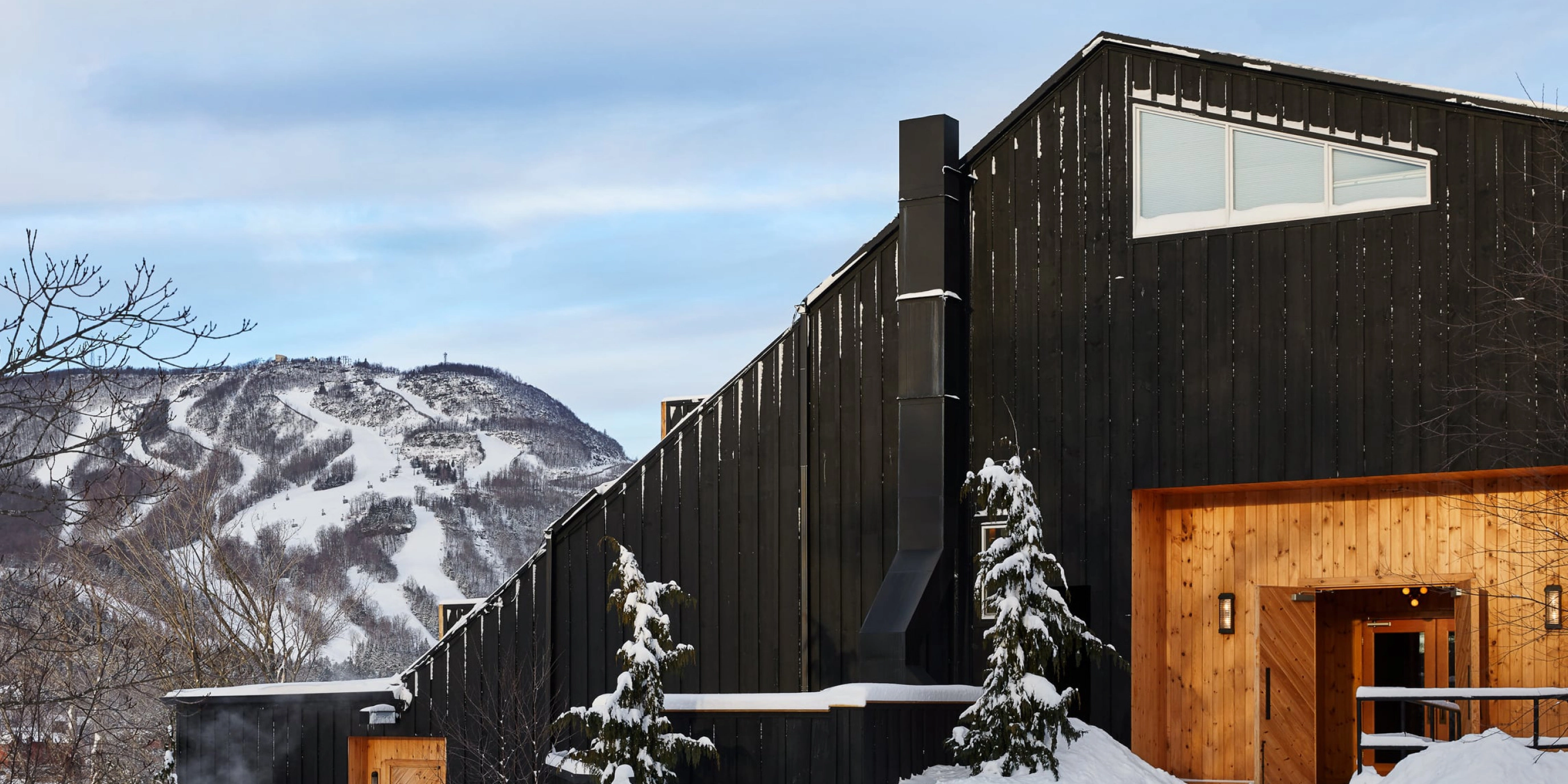 Black cabin exterior in snow with mountain view
