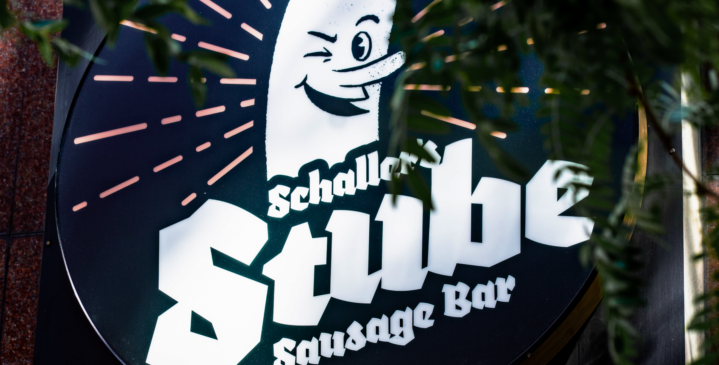Outdoor round sign for the Stube restaurant with a circular version of the logo