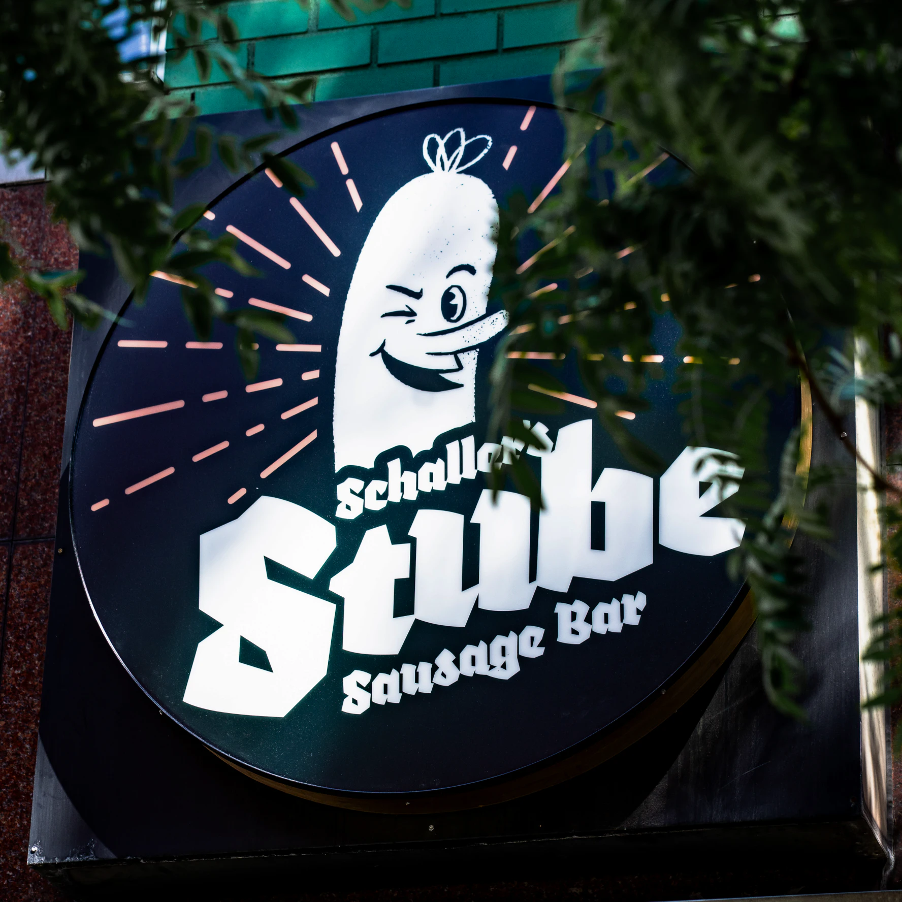Outdoor round sign for the Stube restaurant with a circular version of the logo