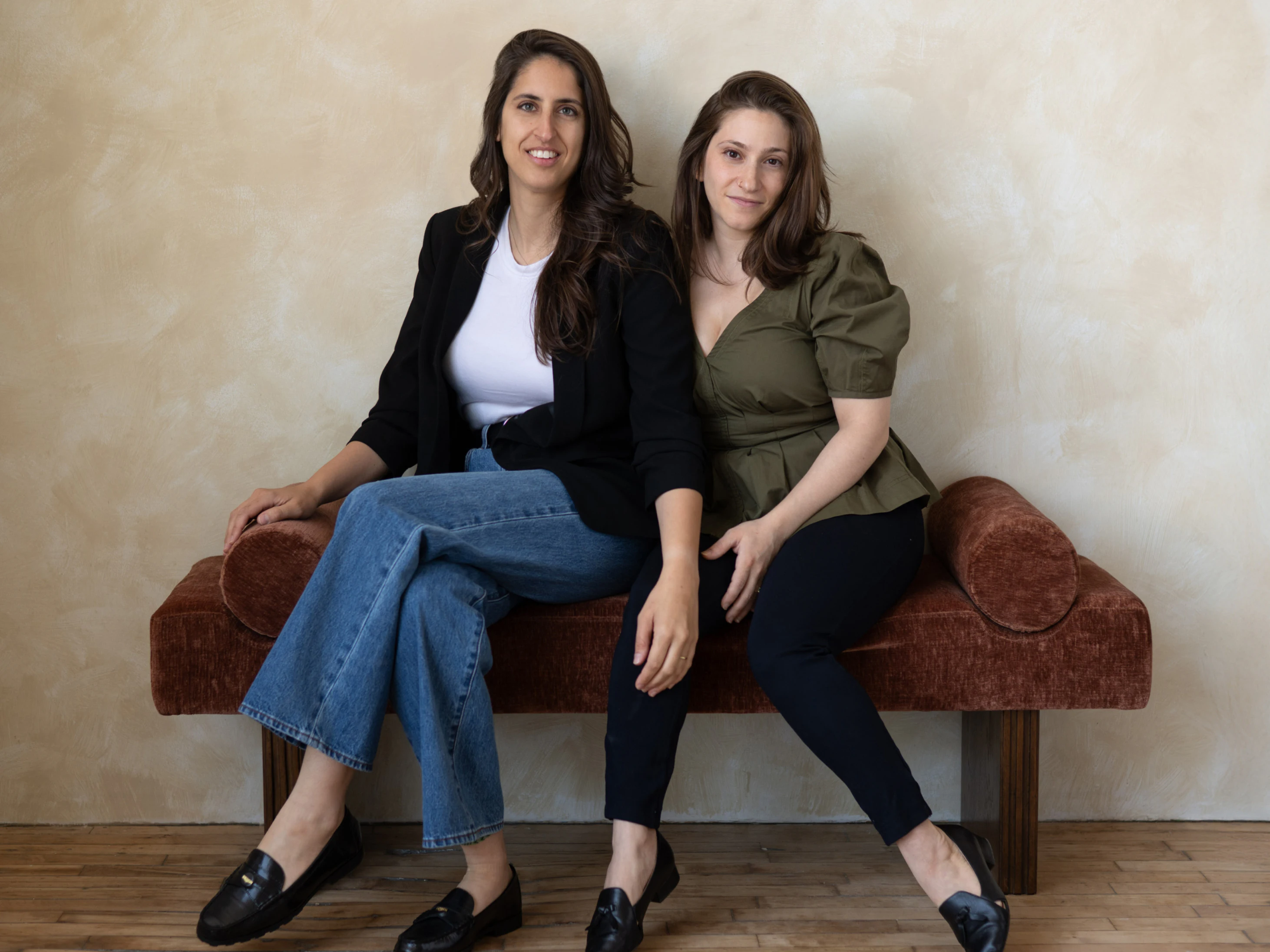 Two women sitting together on a velvet bench