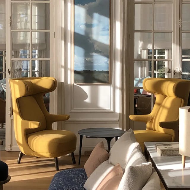 Hôtel, vue intérieur sur le salon, détail sur deux fauteuils jaunes avec tableau au dessus baignés de lumière naturelle.
