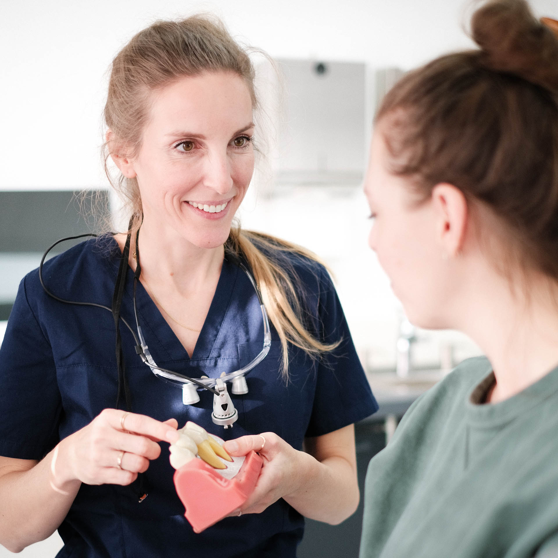 Friederike Kutscher erklärt einer Patientin die Behandlung am Zahnmodell.