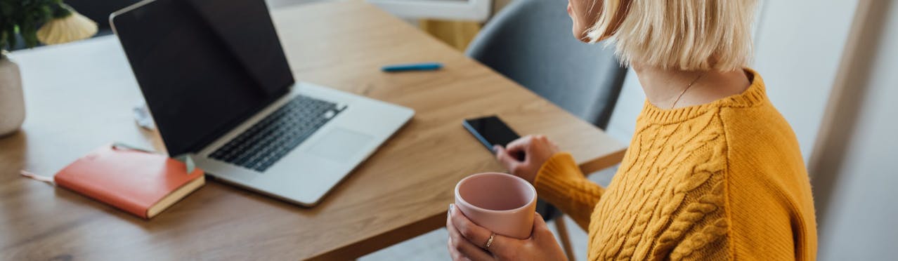 Donna che sorseggia caffè mentre prende cellulare 