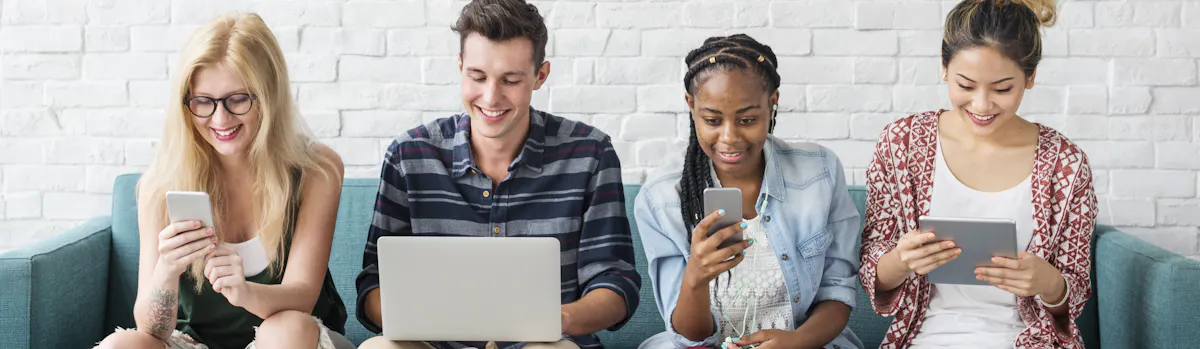3 jeunes femmes et un jeune homme assis sur un canapé bleu regardant chacun leurs smartphones, tablette ou ordinateur 3 jeunes femmes et un jeune homme assis sur un canapé bleu regardant chacun leurs smartphones, tablette ou ordinateur