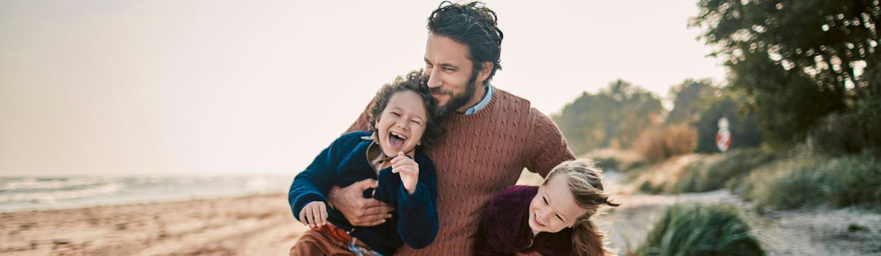 Uomo che solleva figli su spiaggia