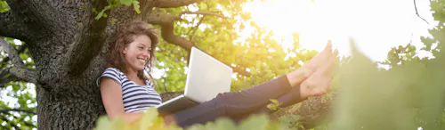 ragazza seduta con pc su un albero ragazza seduta con pc su un albero