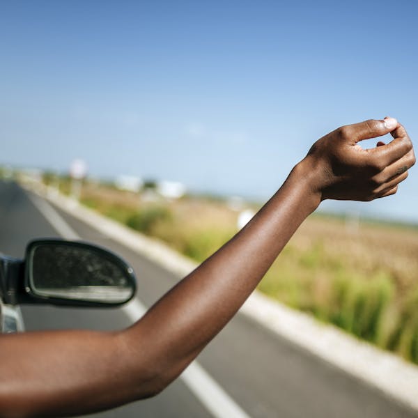 Bras de femme sortant d'une vitre de voiture à la campagne