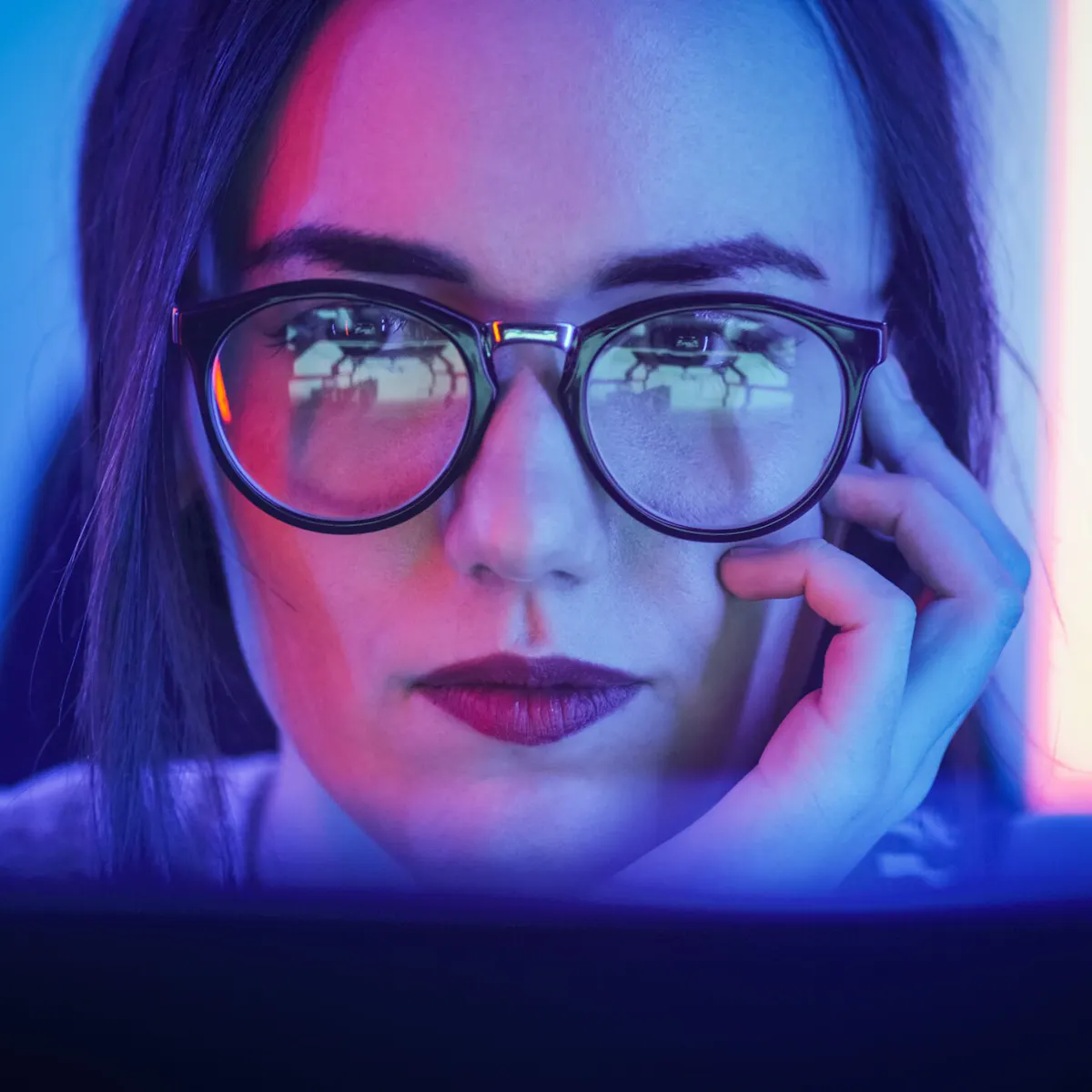 une femme qui porte des lunettes regarde attentivement son écran d'ordinateur une femme qui porte des lunettes regarde attentivement son écran d'ordinateur