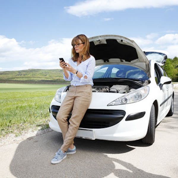 Donna che controlla cellulare con auto ferma