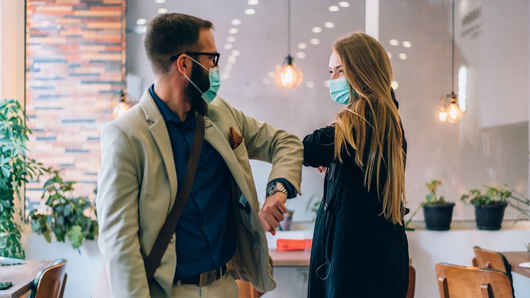 Un homme et une femme portent le masque et se saluent avec le coude