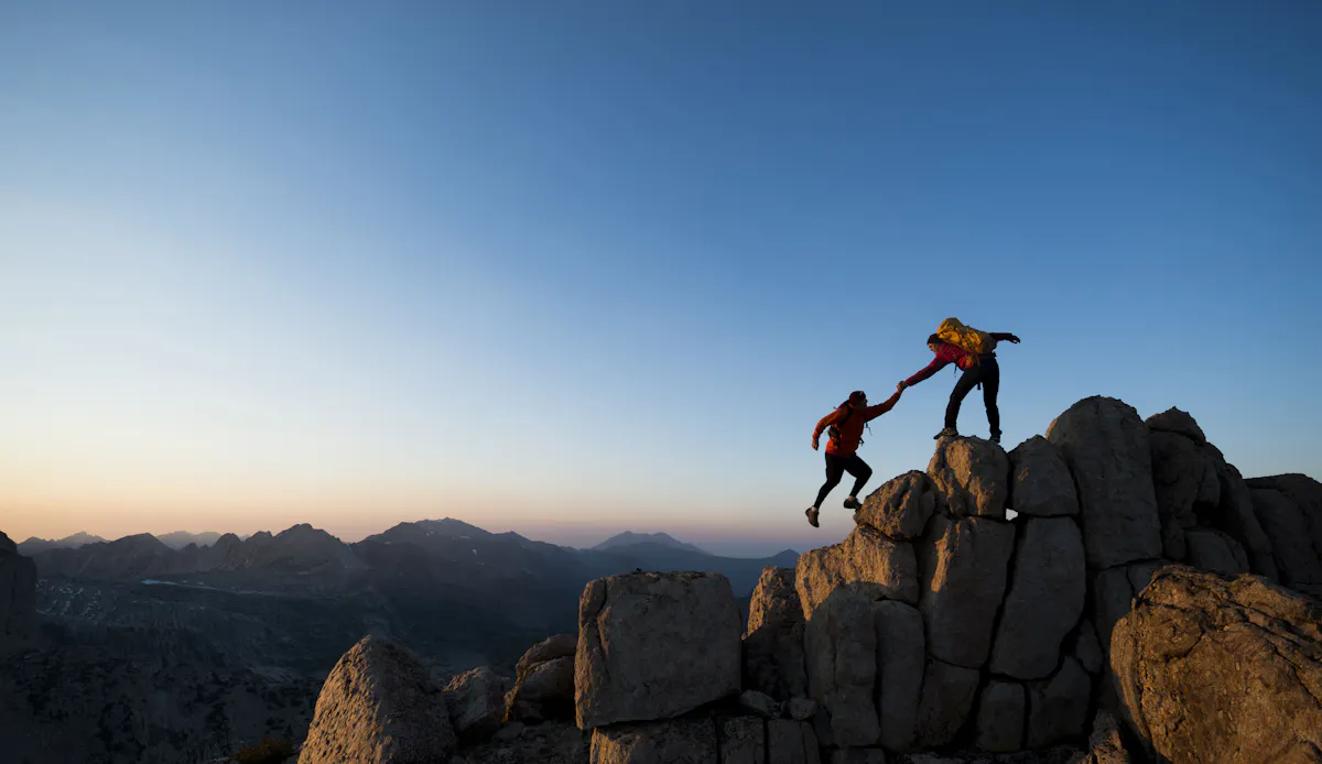 climber helps another climber on a mountain climber helps another climber on a mountain