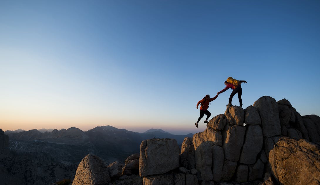 Climber helps another climber on a mountain 