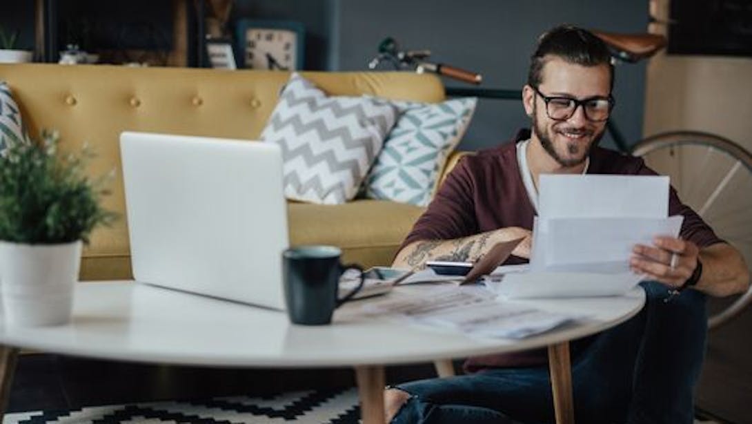 Un homme consulte des documents administratifs devant son ordinateur