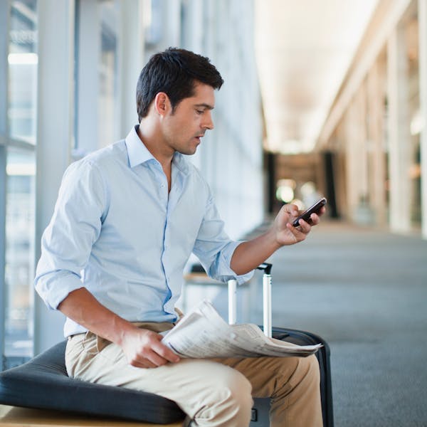 Uomo seduto all'aeroporto con cellulare in mano
