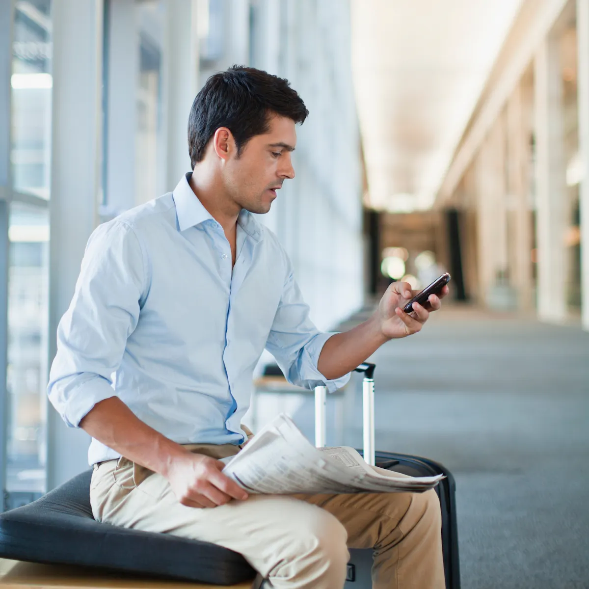 uomo seduto all'aeroporto con cellulare in mano uomo seduto all'aeroporto con cellulare in mano