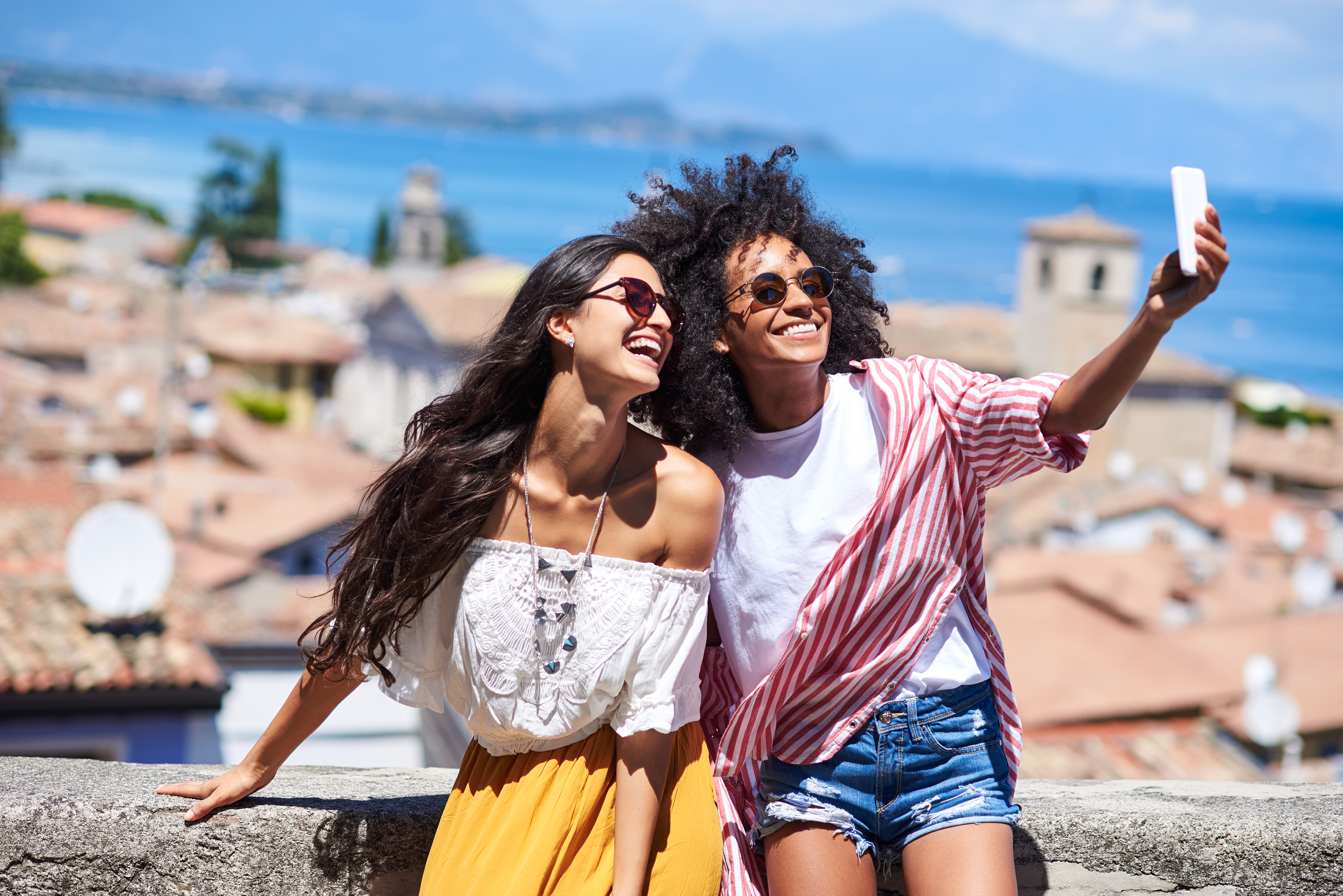 deux femmes en vacances se prennent en photo avec un smartphone devant la mer