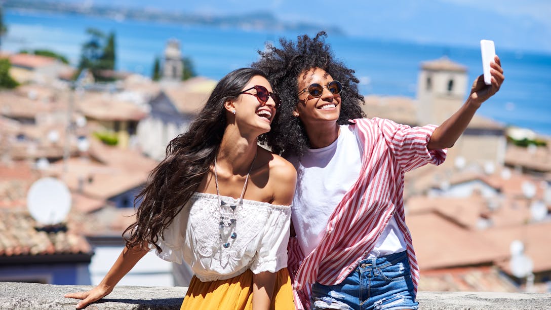Deux femmes en vacances se prennent en photo avec un smartphone devant la mer