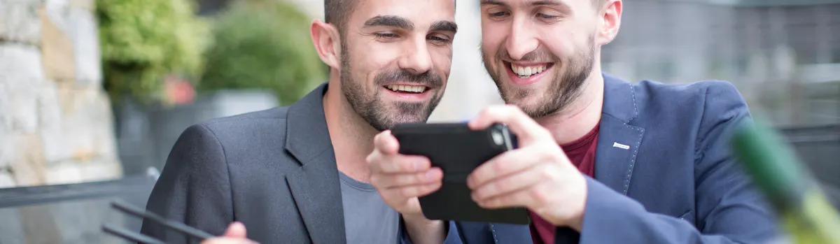 deux hommes regardent une tablette en riant et en mangeant des sushis deux hommes regardent une tablette en riant et en mangeant des sushis