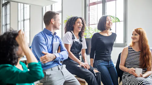 femmes et hommes assis sur une table dans une salle lumineuse femmes et hommes assis sur une table dans une salle lumineuse