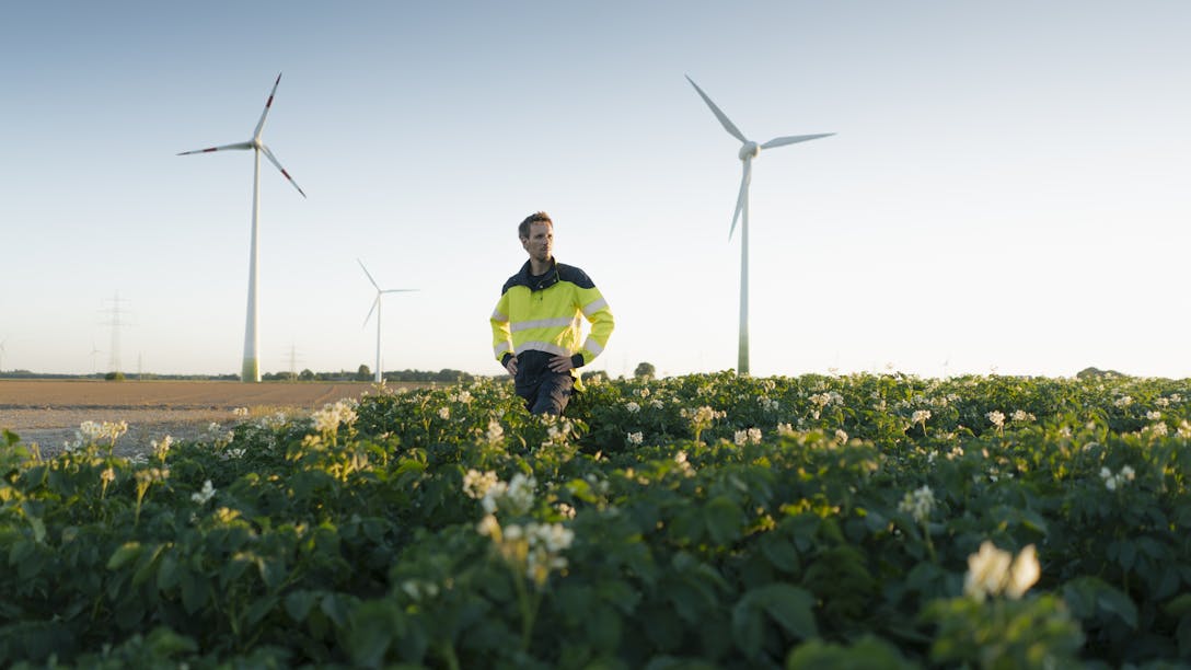 Homme dans un champ avec des éoliennes à l'horizon