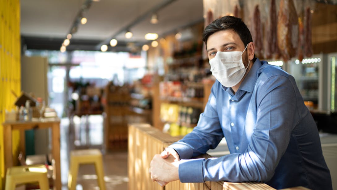 Restaurateur masqué derrière son bar