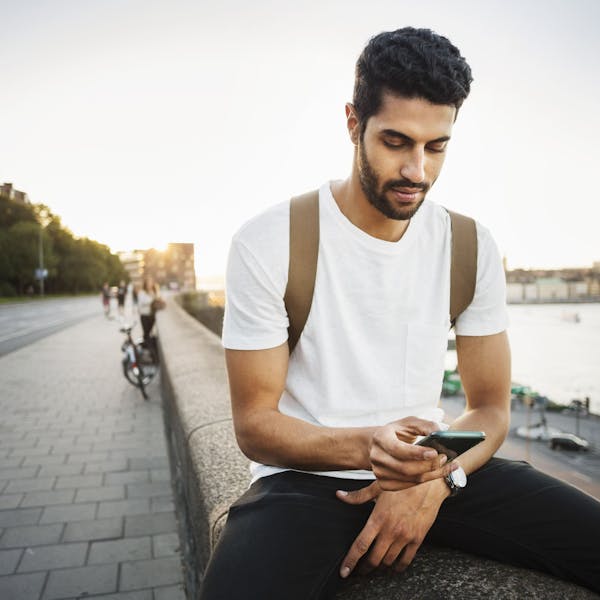 man on riverside is texting
