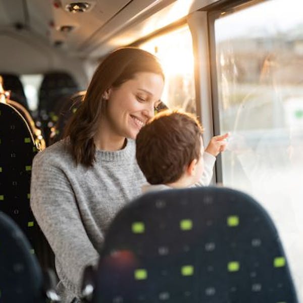 Lächelnde Mutter und ihr kleiner Sohn sitzen in einem Reisebus.