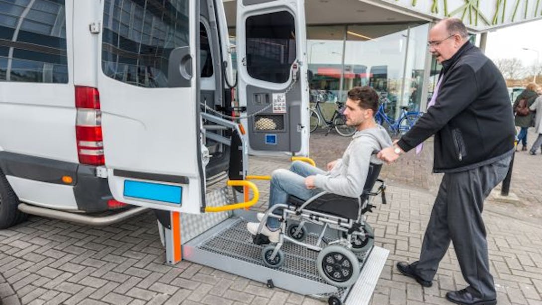 Un homme pousse un jeune homme dans un fauteuil roulant pour l'installer dans une ambulance