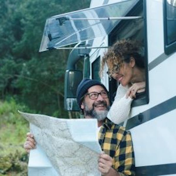 A man and a woman consulting a map in front of a motor home