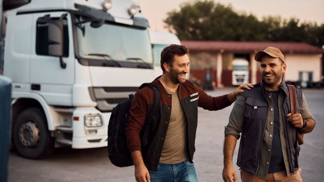 Dwóch kierowców śmieje się przed swoimi samochodami ciężarowymi