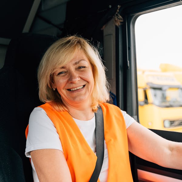 A smiling HGV driver at the wheel of her truck