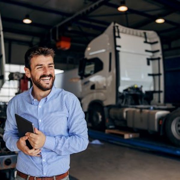 Un hombre ríe delante de un camión mientras sujeta su tableta