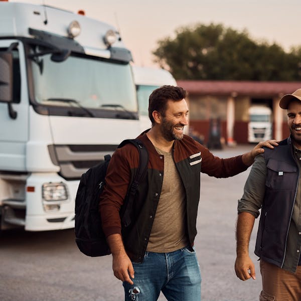 Dos conductores se ríen delante de sus camiones