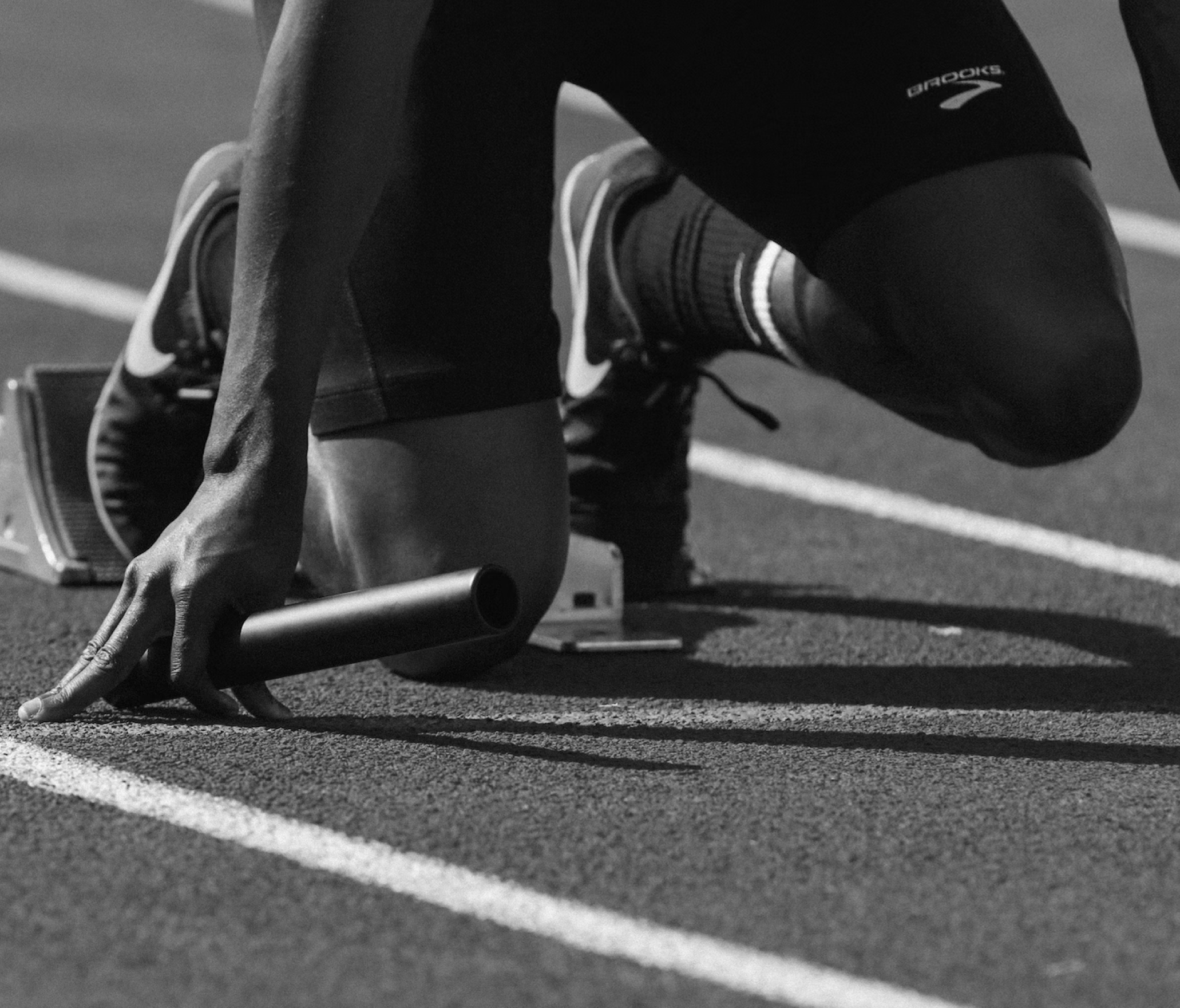A relay runner gets set for the start of a race while holding a baton