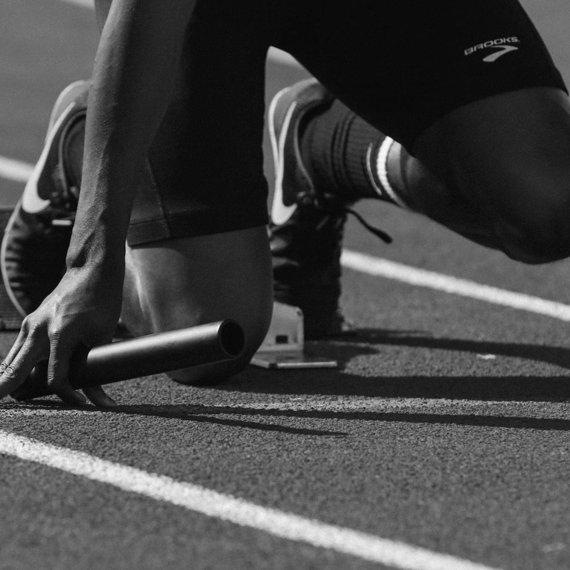 A relay runner gets set for the start of a race while holding a baton