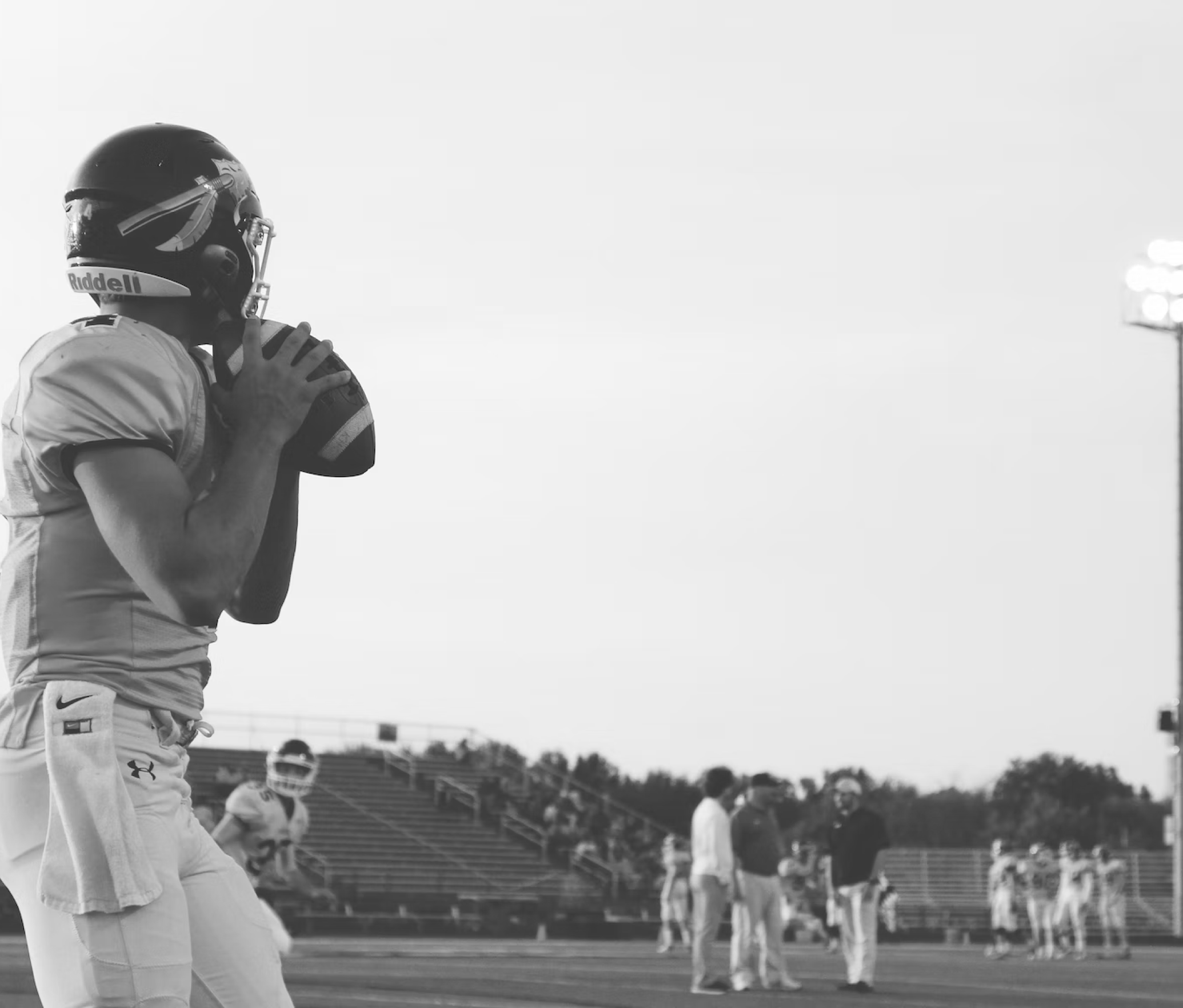 The quarterback of a football team looks for a downfield receiver during his throwing windup
