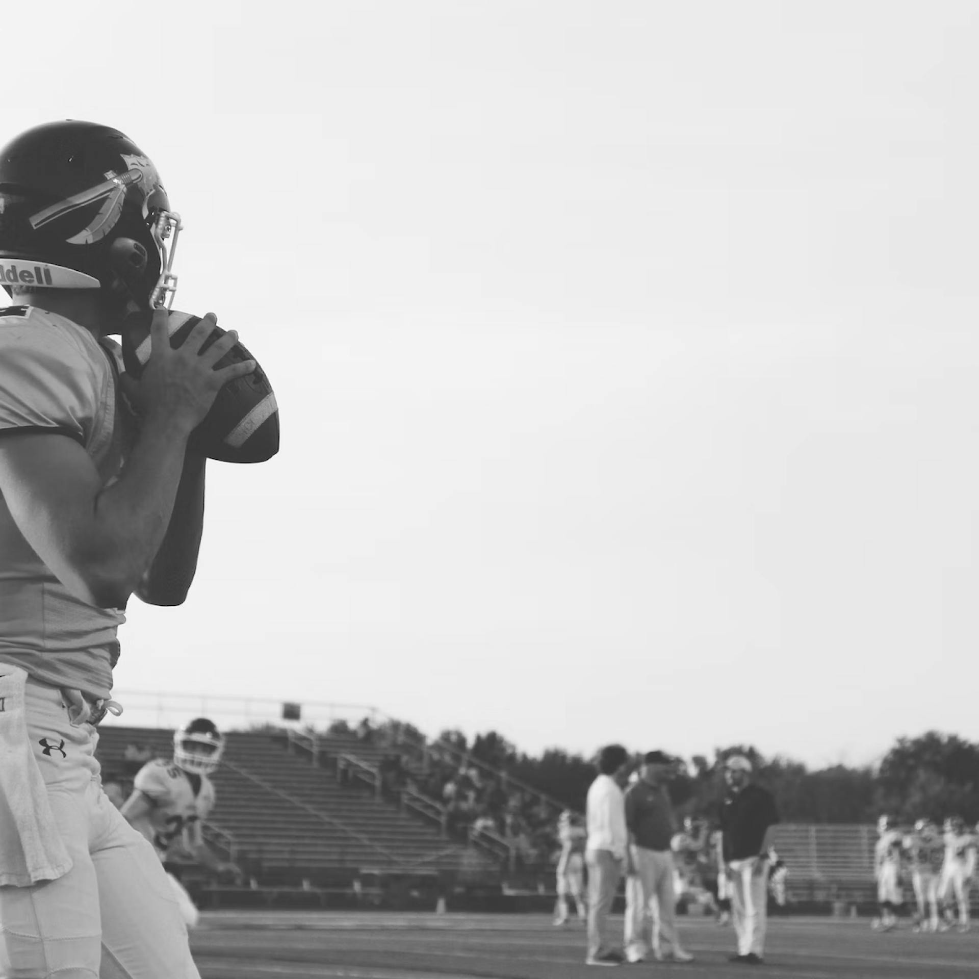 The quarterback of a football team looks for a downfield receiver during his throwing windup