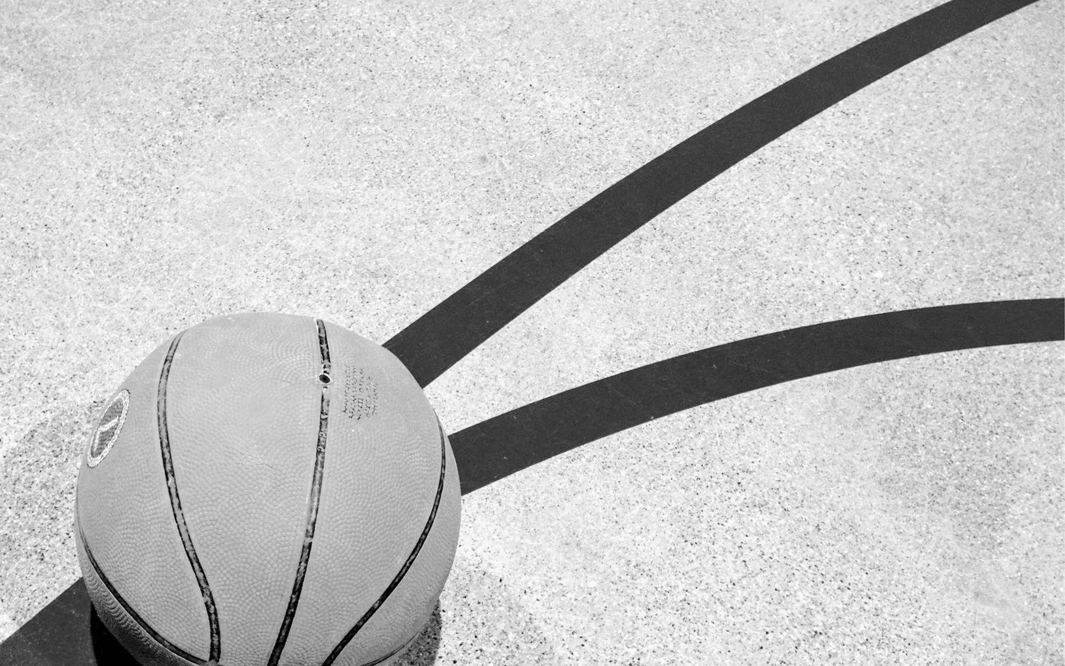Alt Text Basketball on outdoor court with painted lines showing community sports facility